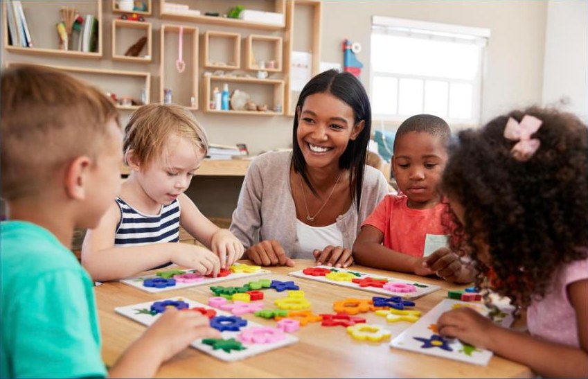 A preschool teacher and pupils with flower-shaped puzzles