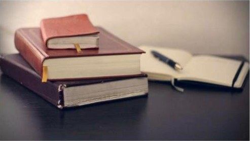 Stack of books and a notebook on a desk