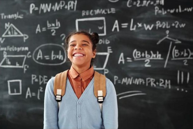 A smiling student in front of a chalkboard of math formulas