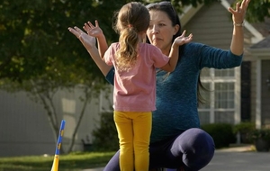 A mother plays with her young daughter outside their home