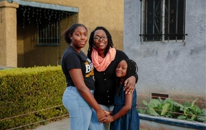 A mother with her two daughters outside their home