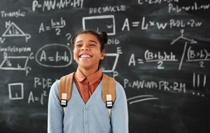 A smiling student in front of a chalkboard of math formulas