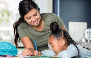 A college-age tutor helps a young student with her work