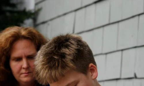 A mother sits with her son as he reads aloud